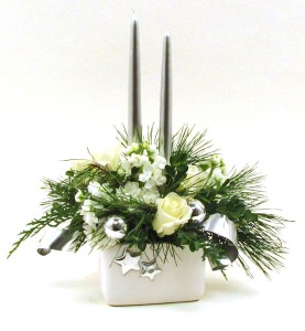 Elegant, winter white roses and stock are designed in a bed of white pine, box wood, and fragrant cedar. Accented with silver decorative wire bands, and silver ornaments , this festive centerpiece is a great gift or decorative piece for your home this holiday season. 