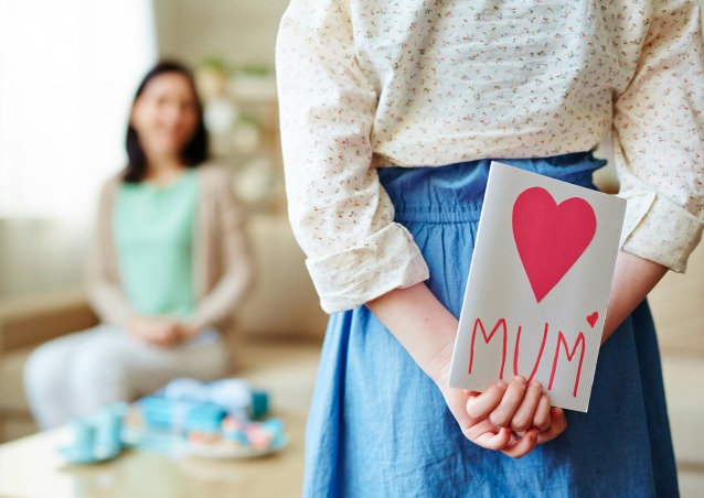 Girl hiding greeting card for mother behind back