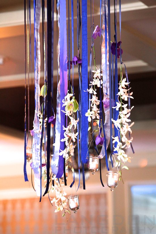 various shades of blue ribbon, votive candles and white orchids were handmade and hung at the reception