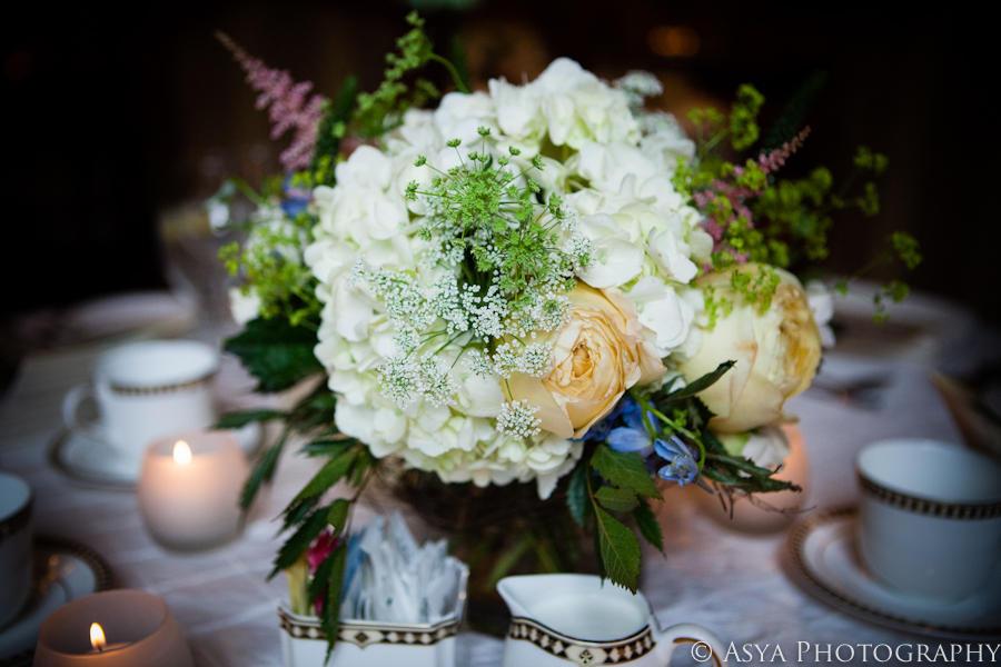 Lush white hydrangea, peach roses and greens filled a glass pedestal revere bowl for the guest table centerpieces