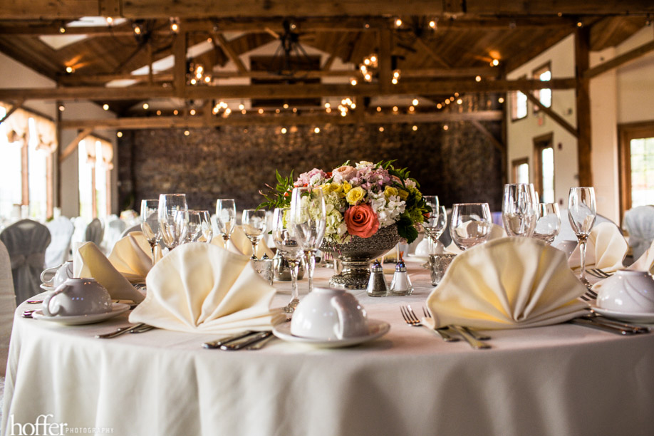Centerpiece of mixed blooms in silver pedestal bowls complemented the somewhat rustic reception space