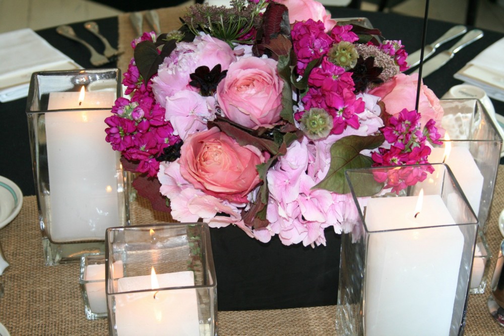 pink flowers in a black vase with candles