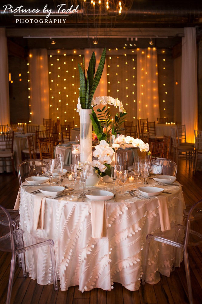 White flowers in white and clear glass vases over a textured white linen