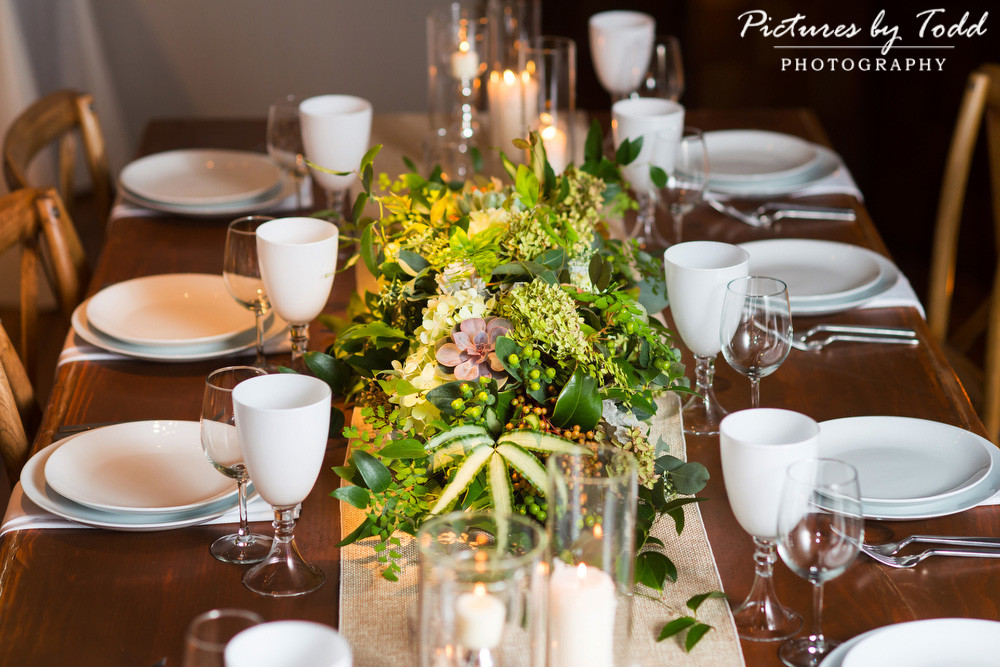 Lush textural centerpiece including succulents on a rustic farm table