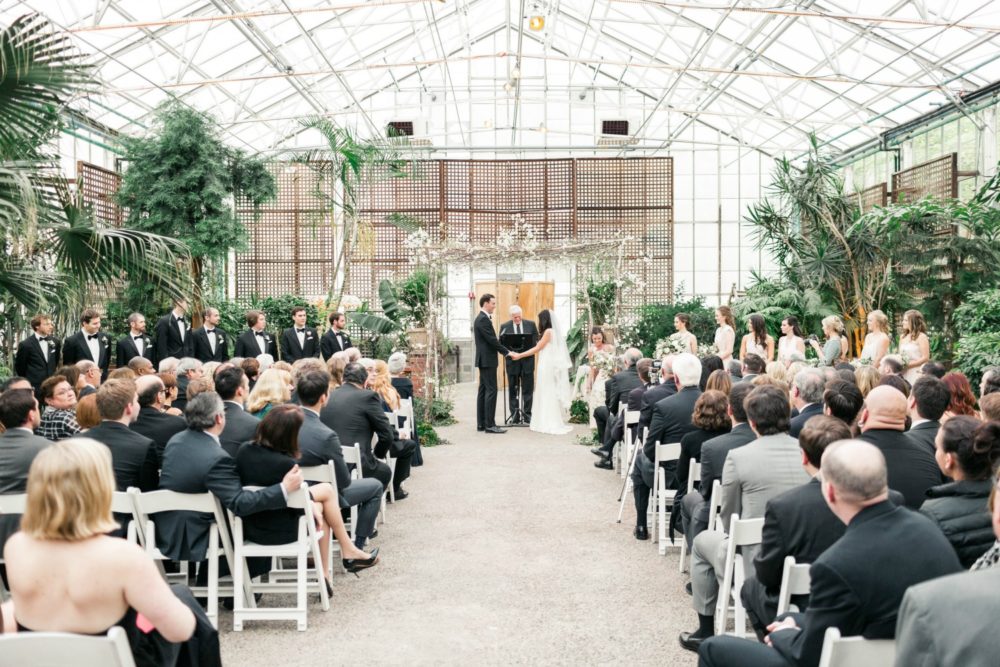 A birch chuppah adorned with textural greenery such as vines, olive leaf, eucalyptus , flowering branches such as dogwood or apple blossoms (or other white or blush bloom **IF available), and large blossoms including peonies and garden roses. We will add vines, foliage, and branches to the top of the chuppah to create a natural, airy canopy. The bases will be finished with plants and moss.